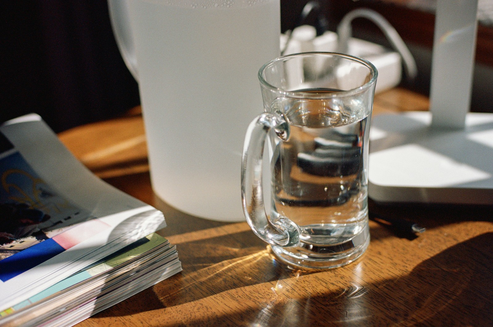 A glass of water sits on a wooden table.