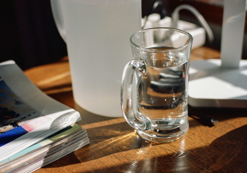 A glass of water sits on a wooden table.